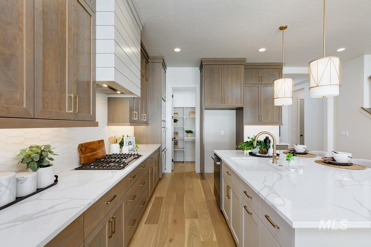 5817 South Gustav Avenue Meridian, ID 83642 - Photo 7 of 33 Modern kitchen featuring wood-finish cabinetry, white quartz countertops, and a full-height tile backsplash