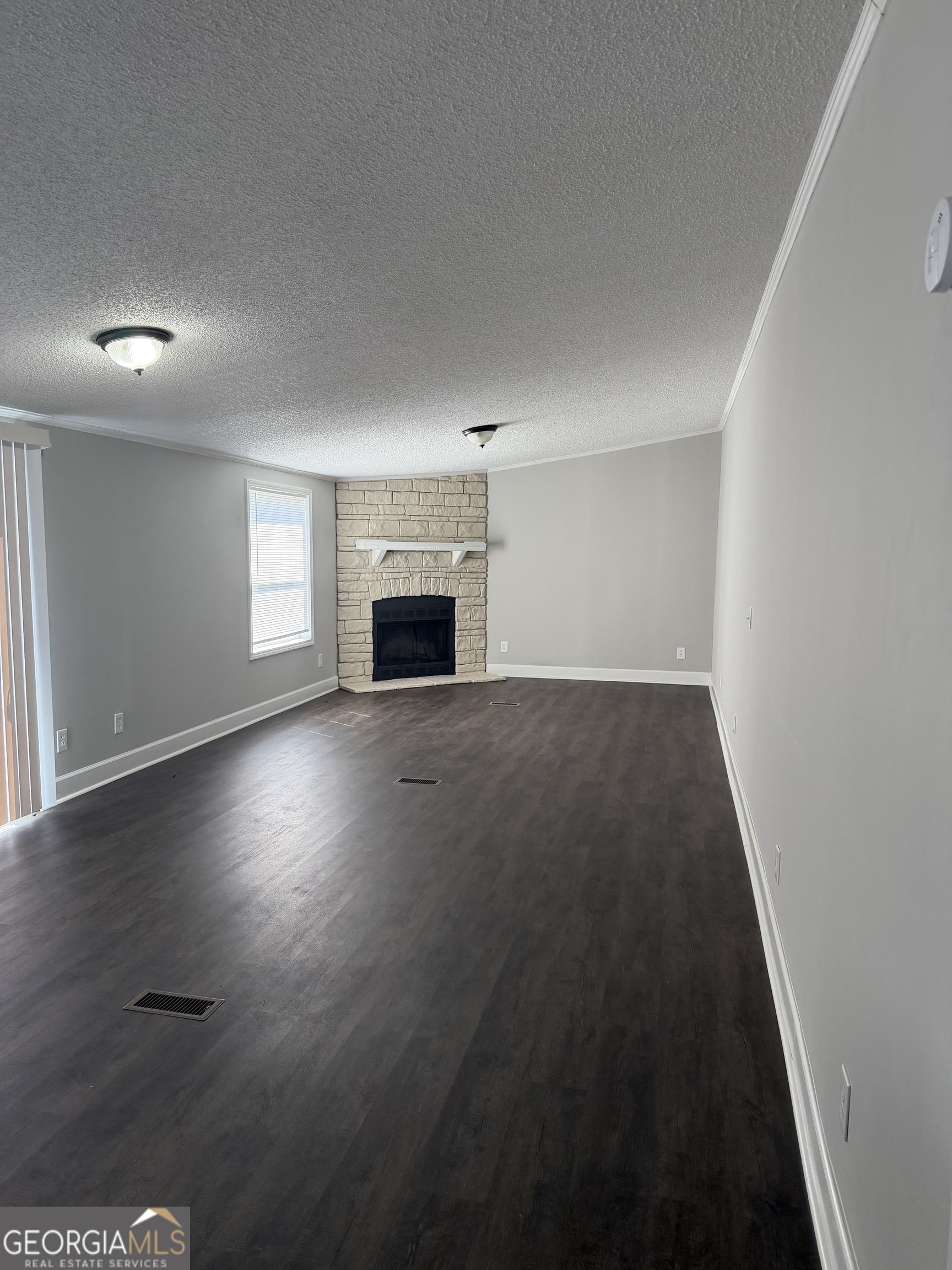 405 Windsor Parkway, Unit 405W Hampton, GA 30228 - Photo 14 of 16 an empty room with wooden floor fireplace and windows