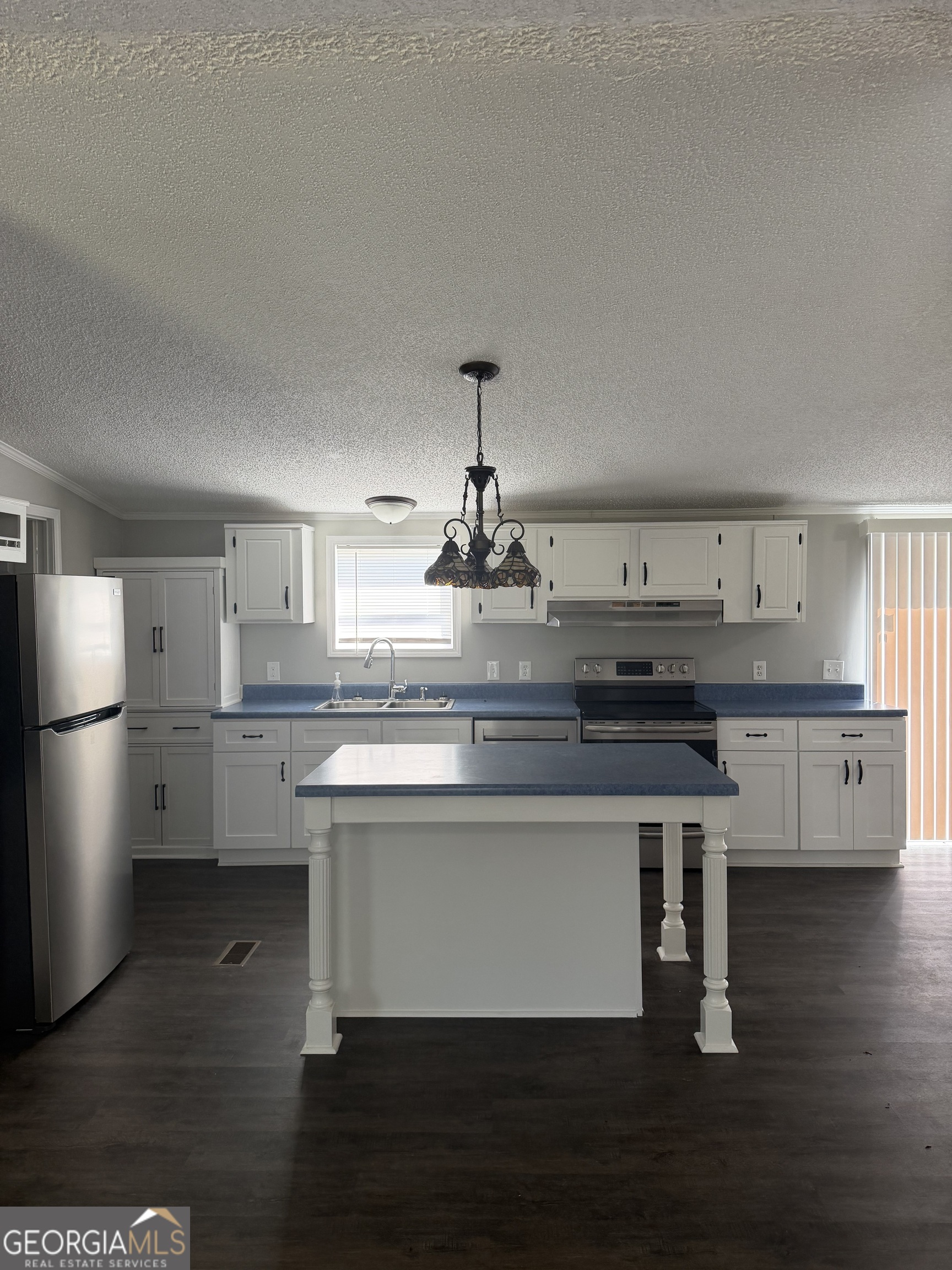 405 Windsor Parkway, Unit 405W Hampton, GA 30228 - Photo 6 of 16 a kitchen with kitchen island granite countertop a sink cabinets and wooden floor