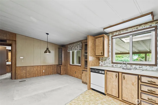 a large white kitchen with granite countertop a large window and a white counter top