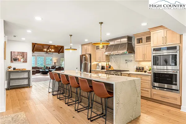 a kitchen with stainless steel appliances granite countertop a stove a sink dishwasher and a refrigerator with wooden floor