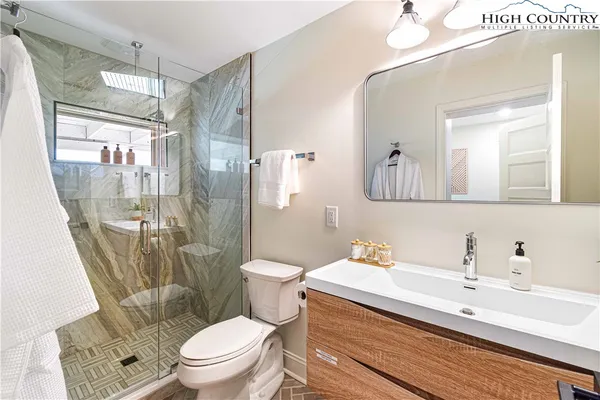 a bathroom with a sink a toilet a glass door shower and a mirror