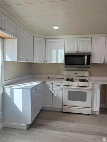 446 Riverside Drive, Unit 24 Wellington, UT 84542 - Photo 7 of 14 Kitchen with gas range gas stove, stainless steel microwave, light countertops, white cabinets, and recessed lighting