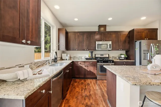 a kitchen with granite countertop a sink a counter top space appliances and cabinets