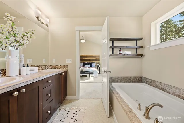 a spacious bathroom with a granite countertop sink a mirror a bathtub and shower