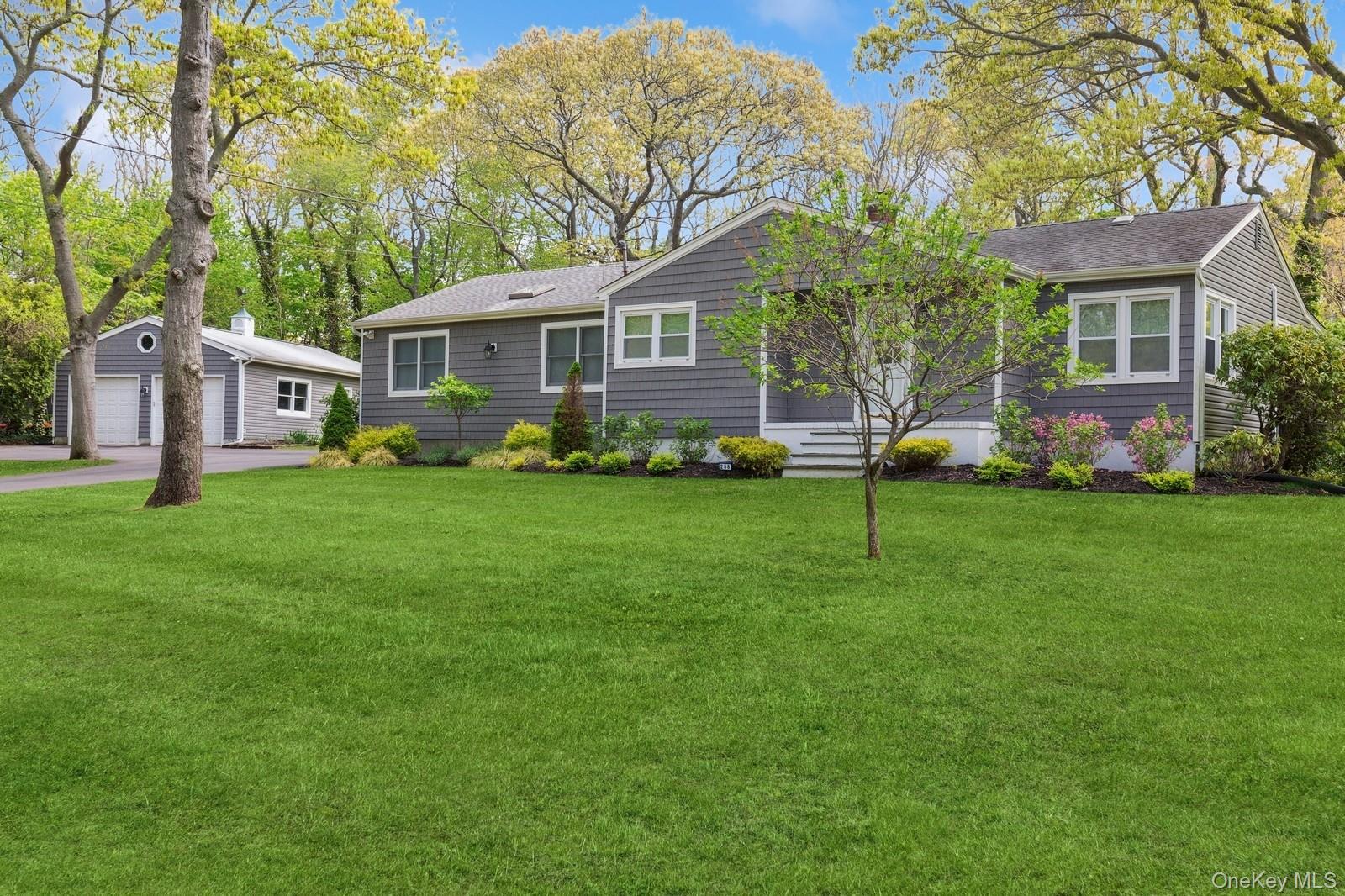 Single story home featuring a front yard, an outbuilding, roof with shingles, and a garage