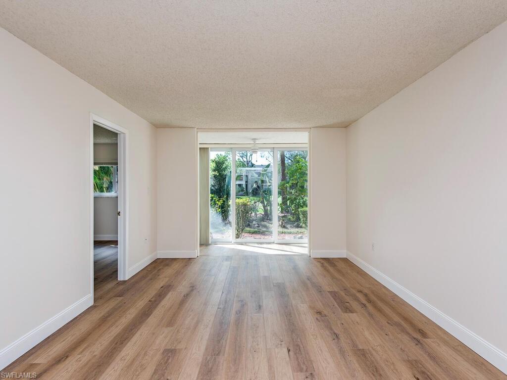180 Turtle Lake Court, Unit 101 Naples, FL 34105 - Photo 1 of 10 wooden floor in an empty room with a window