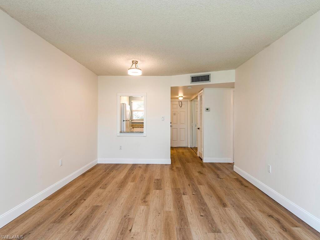 180 Turtle Lake Court, Unit 101 Naples, FL 34105 - Photo 2 of 10 a view of empty room with wooden floor