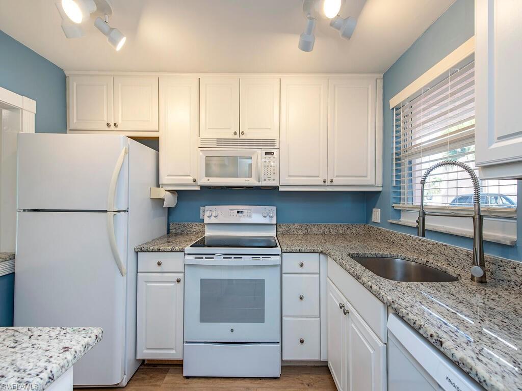 180 Turtle Lake Court, Unit 101 Naples, FL 34105 - Photo 3 of 10 a kitchen with granite countertop a sink stainless steel appliances and cabinets