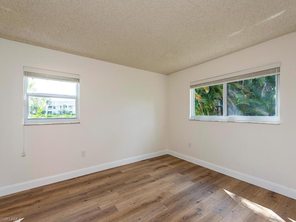 180 Turtle Lake Court, Unit 101 Naples, FL 34105 - Photo 4 of 10 wooden floor in an empty room with a window