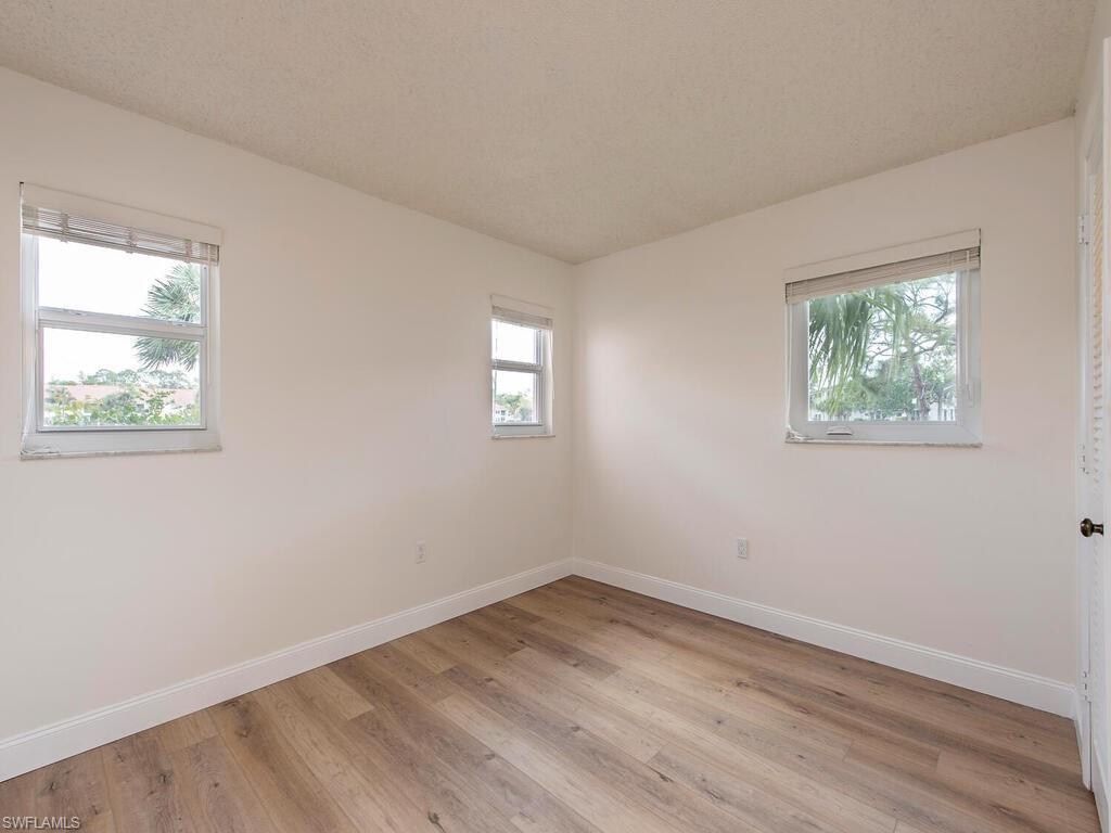 180 Turtle Lake Court, Unit 101 Naples, FL 34105 - Photo 7 of 10 wooden floor in an empty room with a window