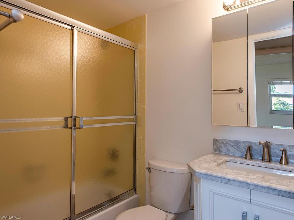 180 Turtle Lake Court, Unit 101 Naples, FL 34105 - Photo 8 of 10 a bathroom with a granite countertop shower mirror and toilet
