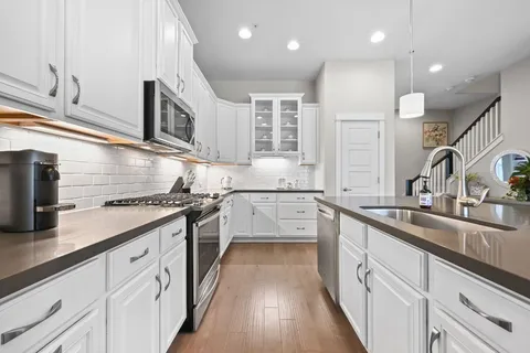 a kitchen with stainless steel appliances granite countertop a sink stove and cabinets