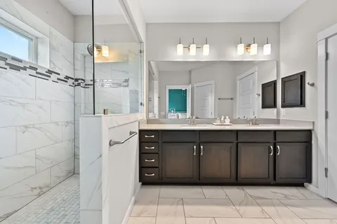 a spacious bathroom with a granite countertop sink mirror and shower