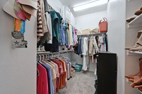 a view of walk in closet with clothes and shoes