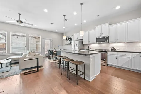 a kitchen with stainless steel appliances granite countertop a stove top oven a sink dishwasher a dining table and chairs with wooden floor