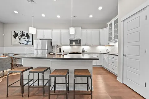 a kitchen with white cabinets and chairs