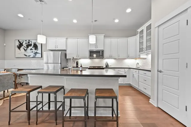a kitchen with white cabinets and chairs