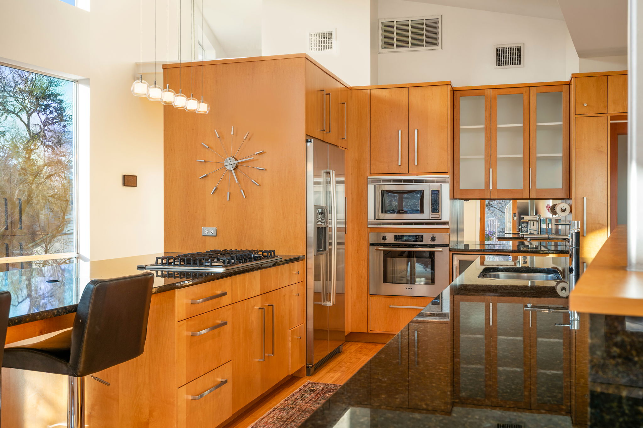 1700 Ravey Street, Unit A Austin, TX 78704 - Photo 14 of 40 Kitchen featuring dark stone countertops, stainless steel appliances, decorative light fixtures, wood finish cabinets, and light wood-style floors