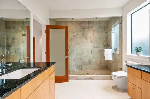 a bathroom with a granite countertop sink toilet and shower