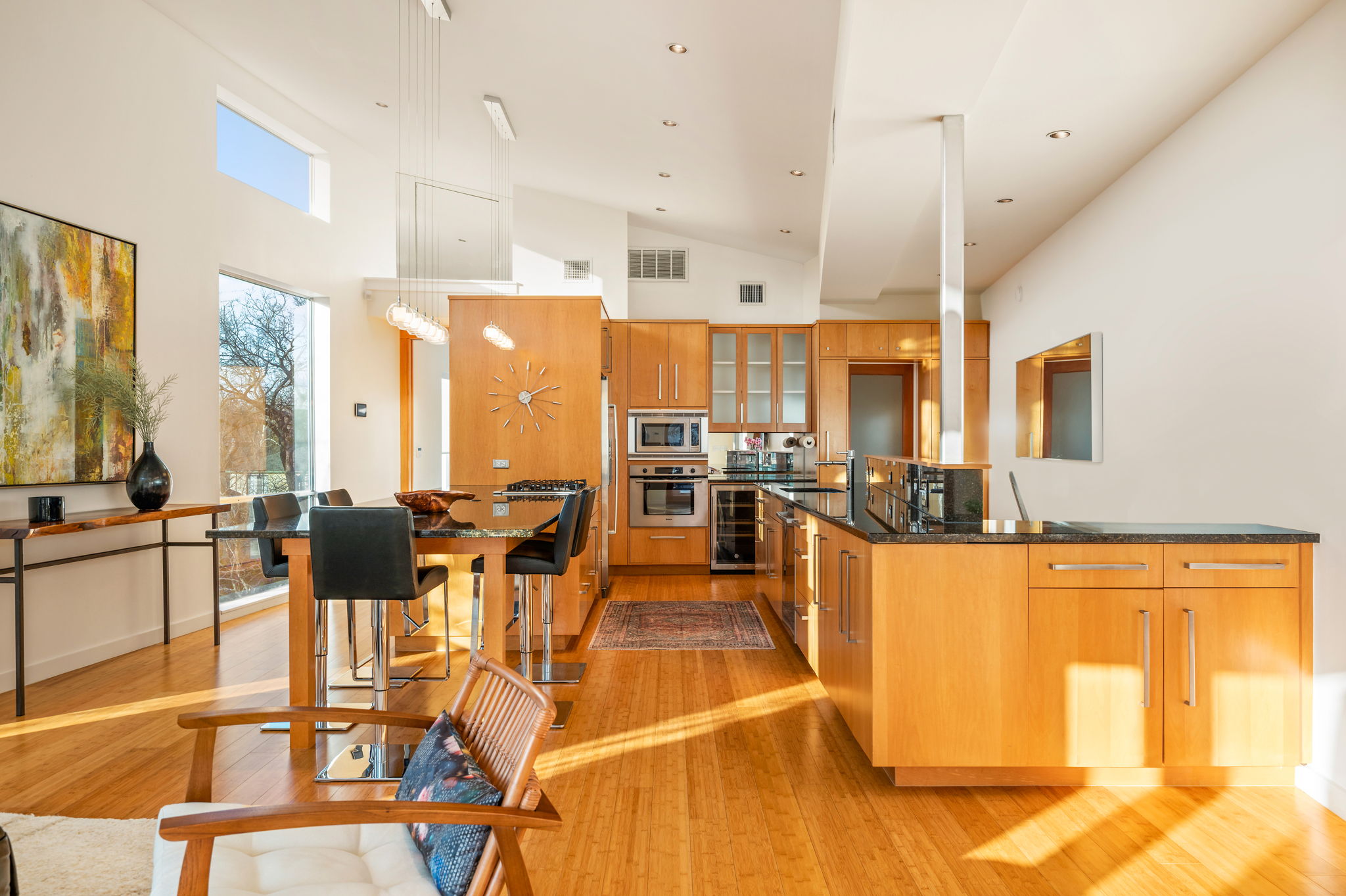 1700 Ravey Street, Unit A Austin, TX 78704 - Photo 4 of 40 Kitchen with glass insert cabinets, a large island, dark stone countertops, light wood finished floors, and stainless steel appliances