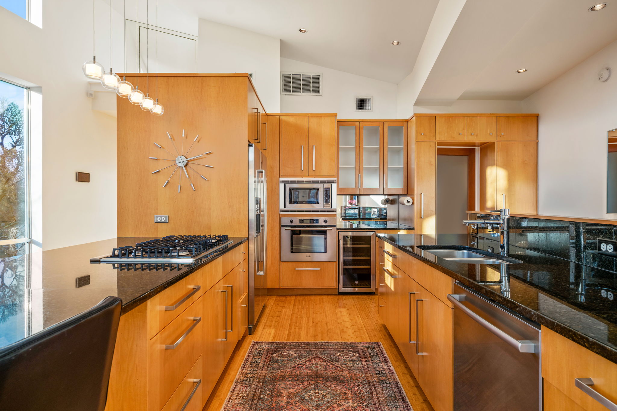 1700 Ravey Street, Unit A Austin, TX 78704 - Photo 6 of 40 Kitchen with dark stone countertops, stainless steel appliances, glass fronted cabinets, beverage cooler, and light wood-style floors
