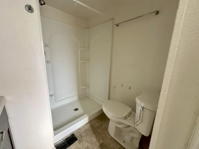 a bathroom with a granite countertop toilet and a shower