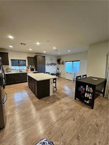 a living room with stainless steel appliances kitchen island granite countertop a table chairs and a refrigerator