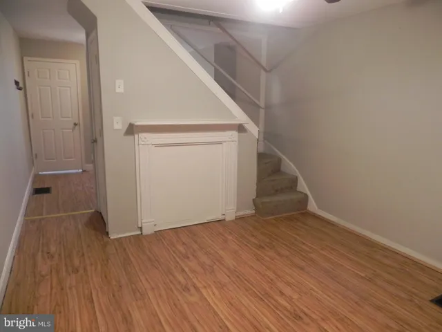 a view of an empty room with wooden floor and entryway