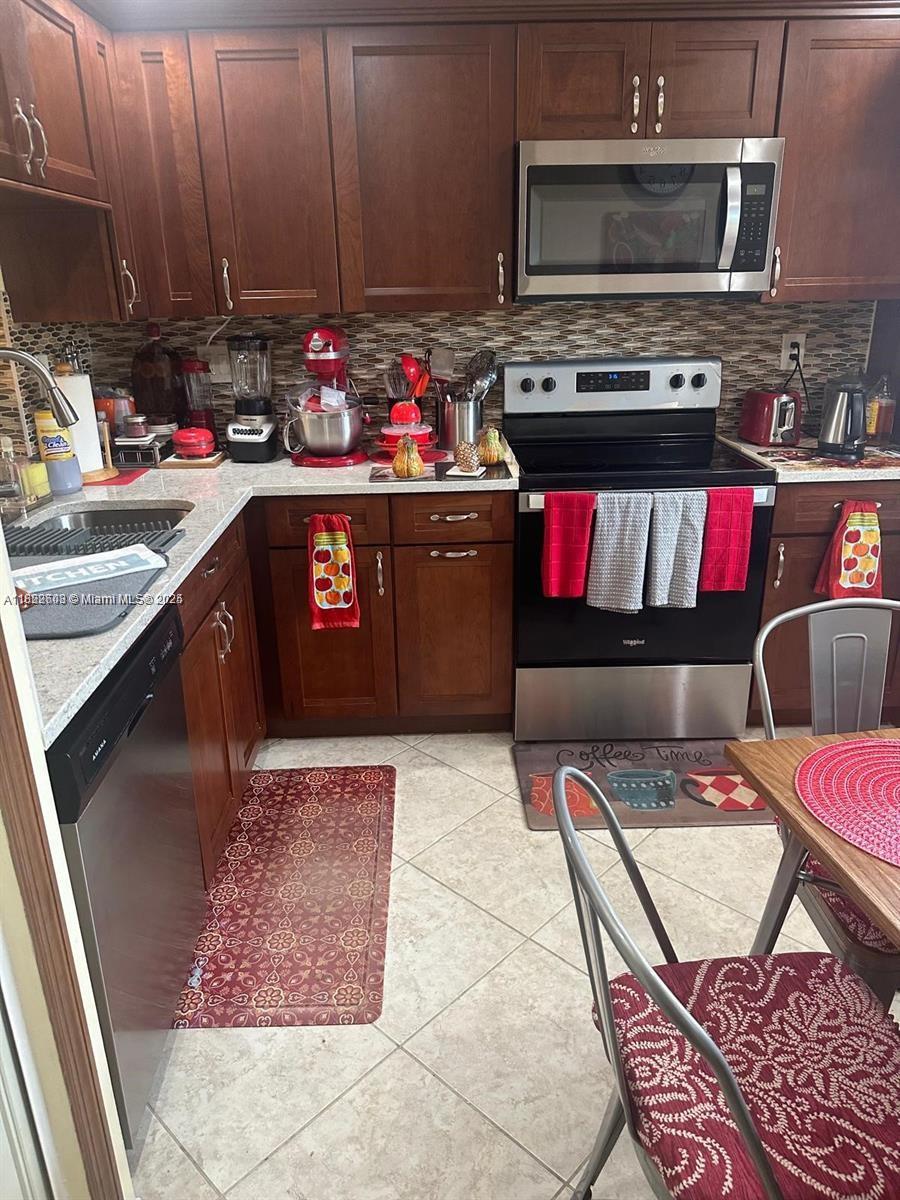 8834 West McNab Road, Unit 302 Tamarac, FL 33321 - Photo 11 of 25 a kitchen with stainless steel appliances granite countertop a stove a sink and a microwave