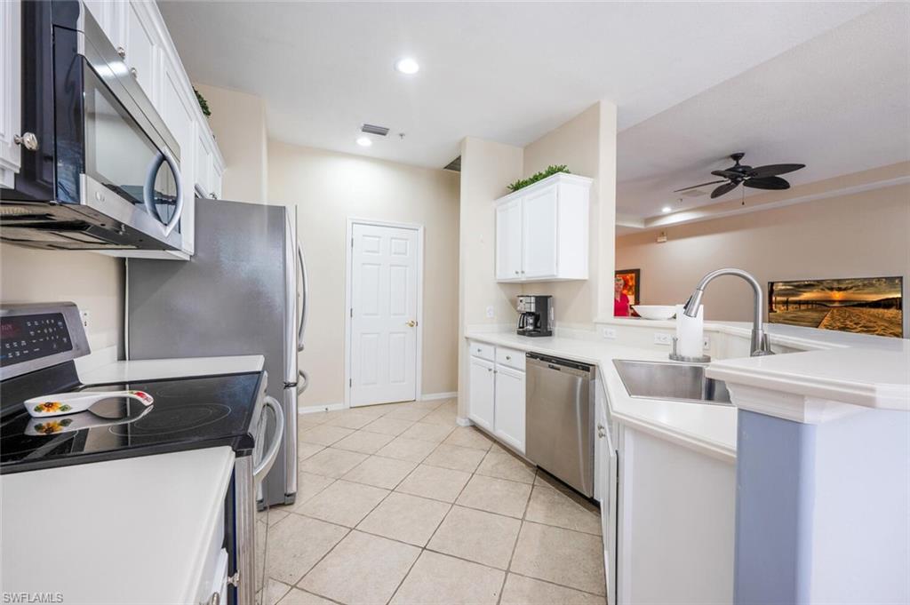 4630 Winged Foot Court, Unit 202 Naples, FL 34112 - Photo 13 of 32 Kitchen featuring a peninsula, a sink, appliances with stainless steel finishes, and white cabinetry