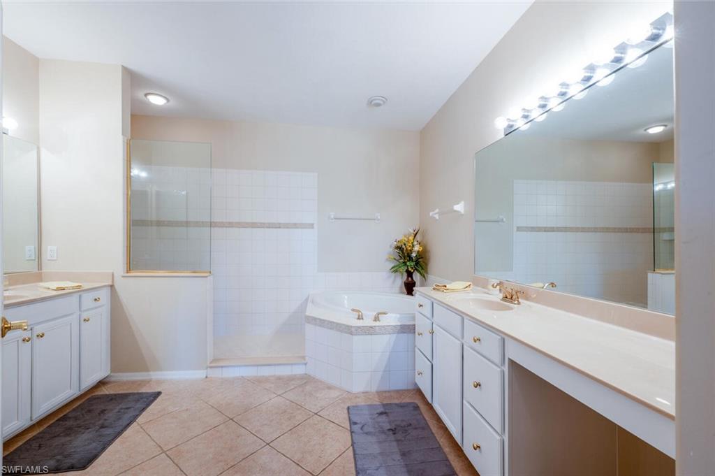 4630 Winged Foot Court, Unit 202 Naples, FL 34112 - Photo 18 of 32 Bathroom with a garden tub, two vanities, a sink, and tile patterned floors