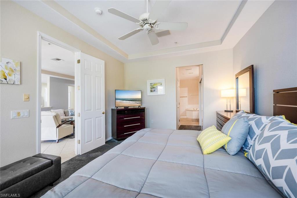 4630 Winged Foot Court, Unit 202 Naples, FL 34112 - Photo 20 of 32 Bedroom with connected bathroom, light carpet, visible vents, a ceiling fan, and a tray ceiling