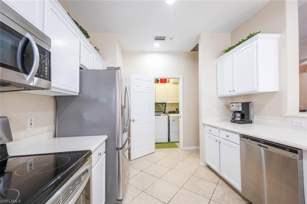 4630 Winged Foot Court, Unit 202 Naples, FL 34112 - Photo 22 of 32 Kitchen with white cabinets, stainless steel appliances, and separate washer and dryer