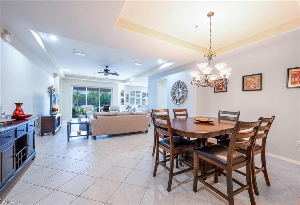 4630 Winged Foot Court, Unit 202 Naples, FL 34112 - Photo 9 of 32 Dining room with light tile patterned flooring, a raised ceiling, and ceiling fan with notable chandelier