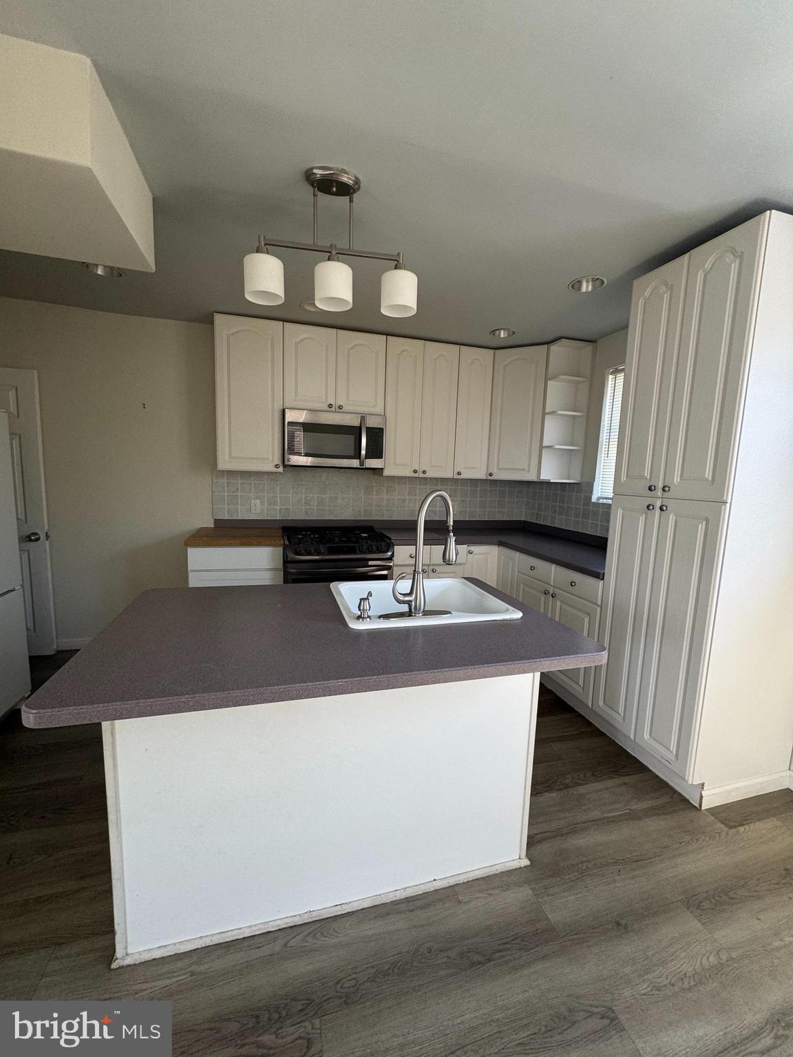 4215 Lansing Street Philadelphia, PA 19136 - Photo 3 of 14 a kitchen with kitchen island granite countertop a sink a stove a refrigerator cabinets and a dining table
