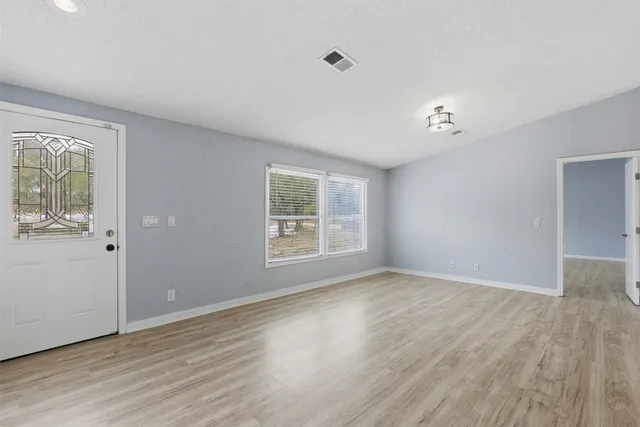 a view of an empty room with wooden floor and a window