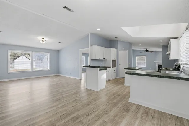 a kitchen with stainless steel appliances granite countertop a sink a stove a refrigerator and island with wooden floor