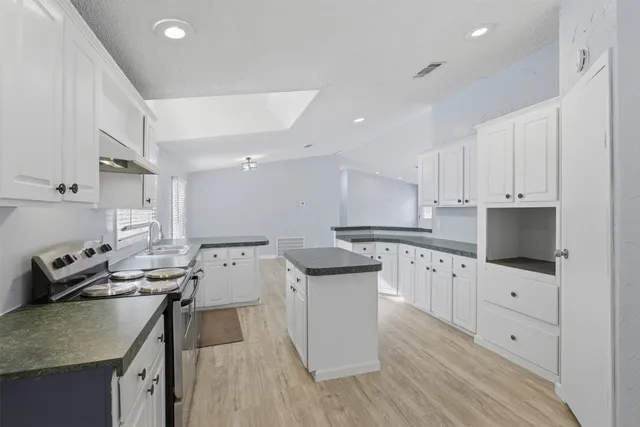 a kitchen with granite countertop a sink stove and cabinets
