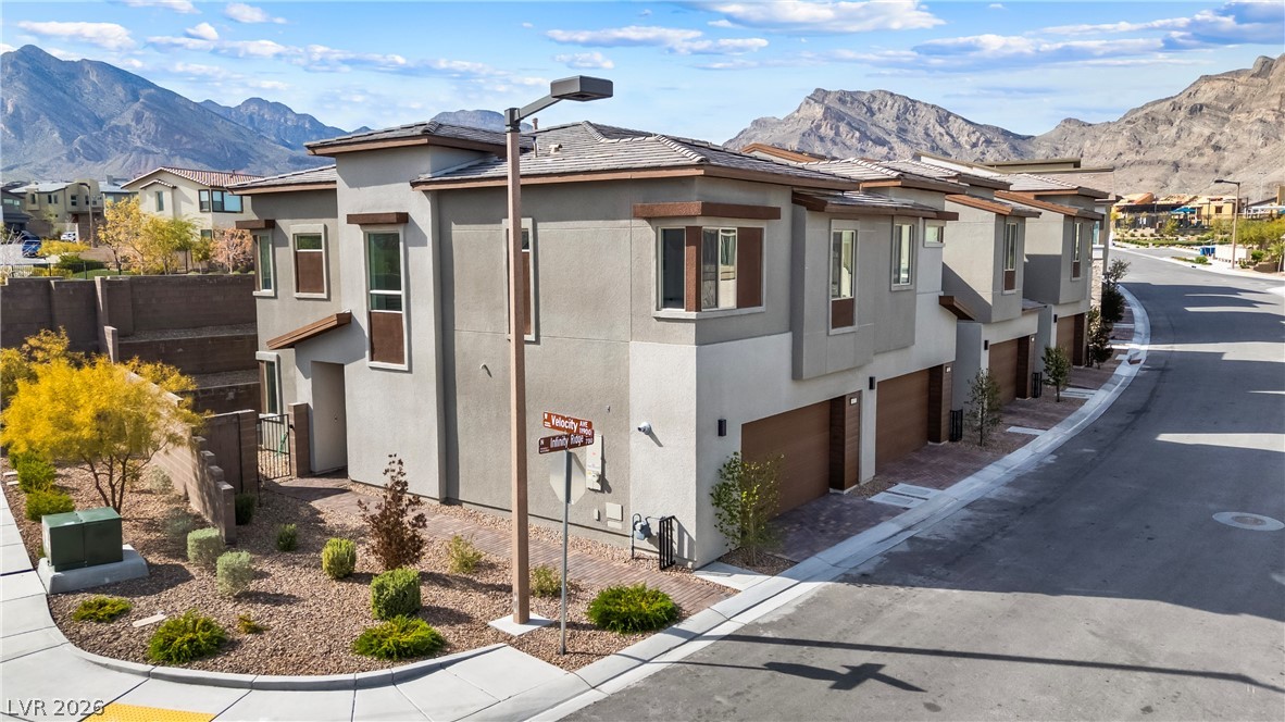 View of home's exterior with stucco siding, a garage, a mountain view, and a residential view