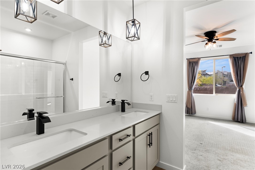 633 Infinity Rdg Street Las Vegas, NV 89138 - Photo 11 of 36 Full bath featuring double vanity, carpet floors, a stall shower, and a ceiling fan