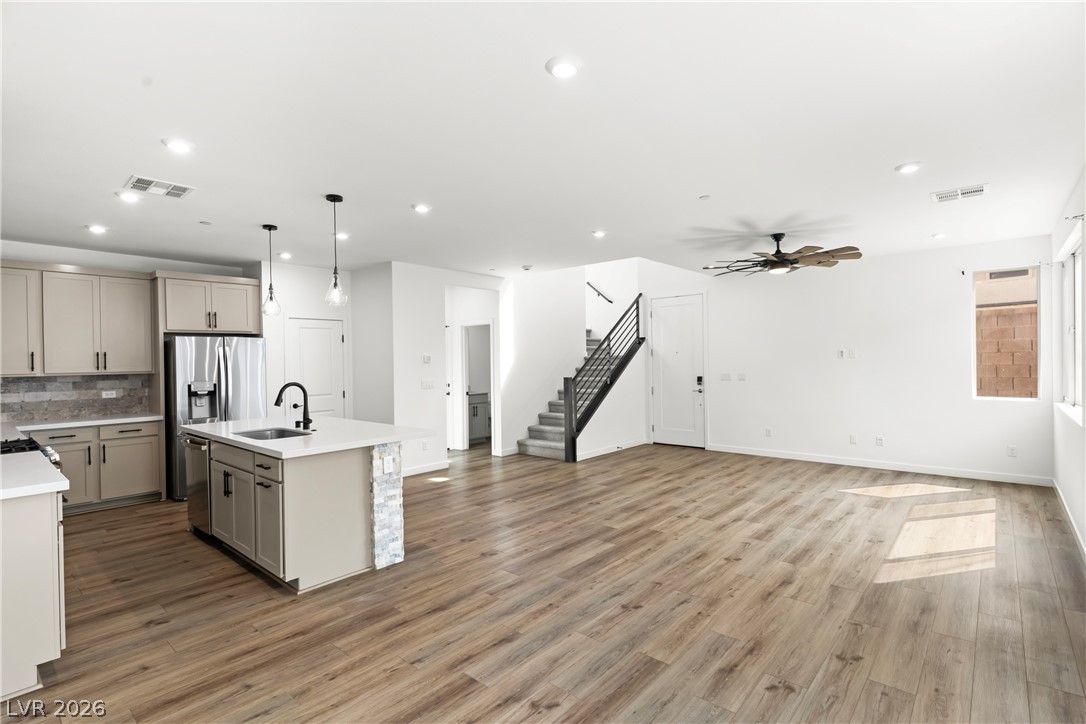 633 Infinity Rdg Street Las Vegas, NV 89138 - Photo 32 of 36 Kitchen with a kitchen island with sink, gray cabinetry, open floor plan, decorative light fixtures, and light wood finished floors