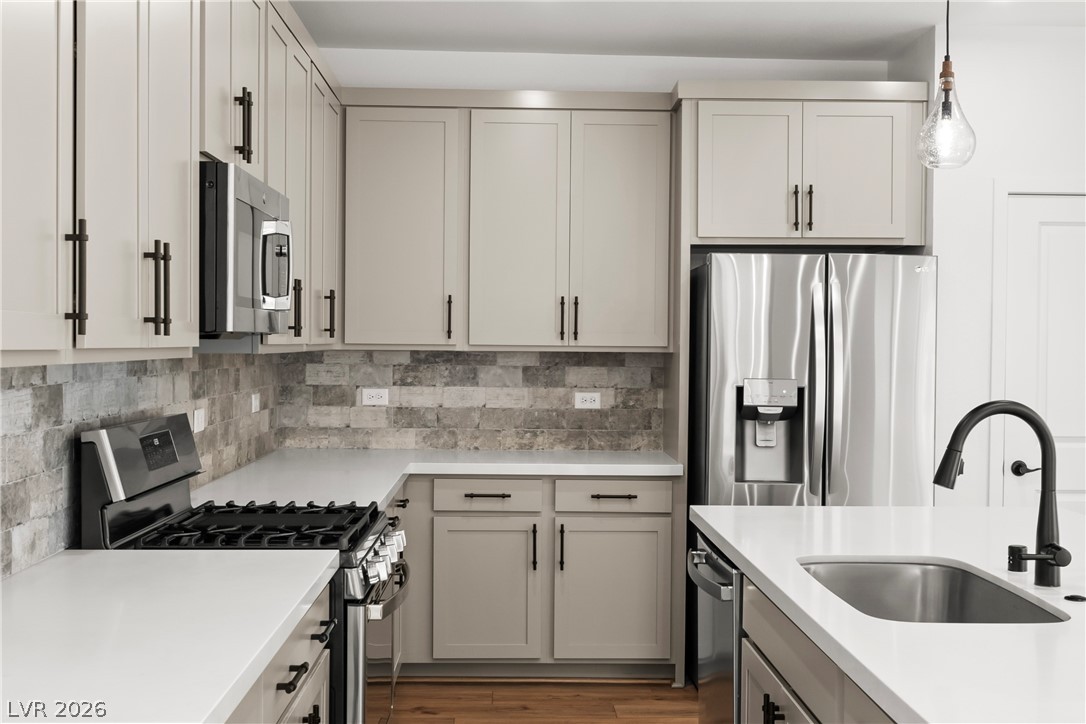 633 Infinity Rdg Street Las Vegas, NV 89138 - Photo 4 of 36 Kitchen featuring stainless steel appliances, backsplash, hanging light fixtures, light wood-style floors, and gray cabinetry