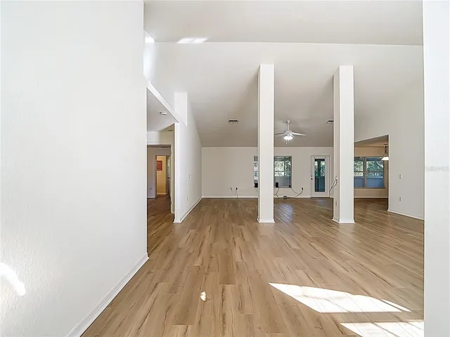 a view of an empty room with chandelier fan and a window
