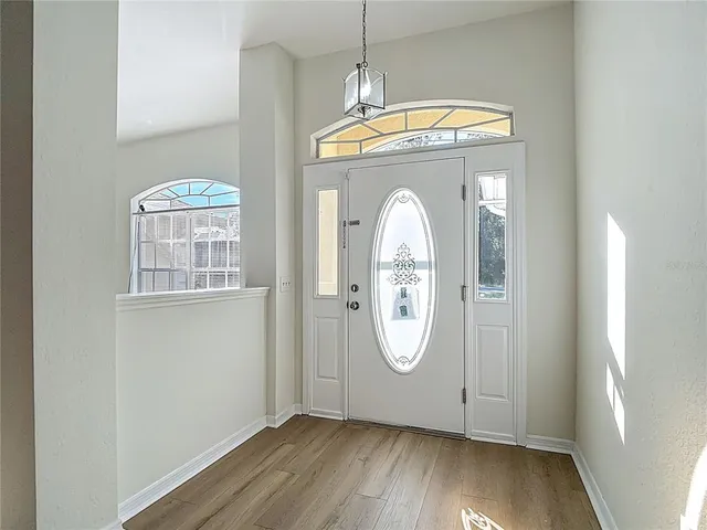 a view of an empty room with wooden floor and a ceiling fan