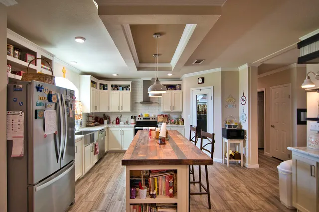 a kitchen with stainless steel appliances granite countertop a refrigerator a stove top oven a sink dishwasher and white cabinets with wooden floor