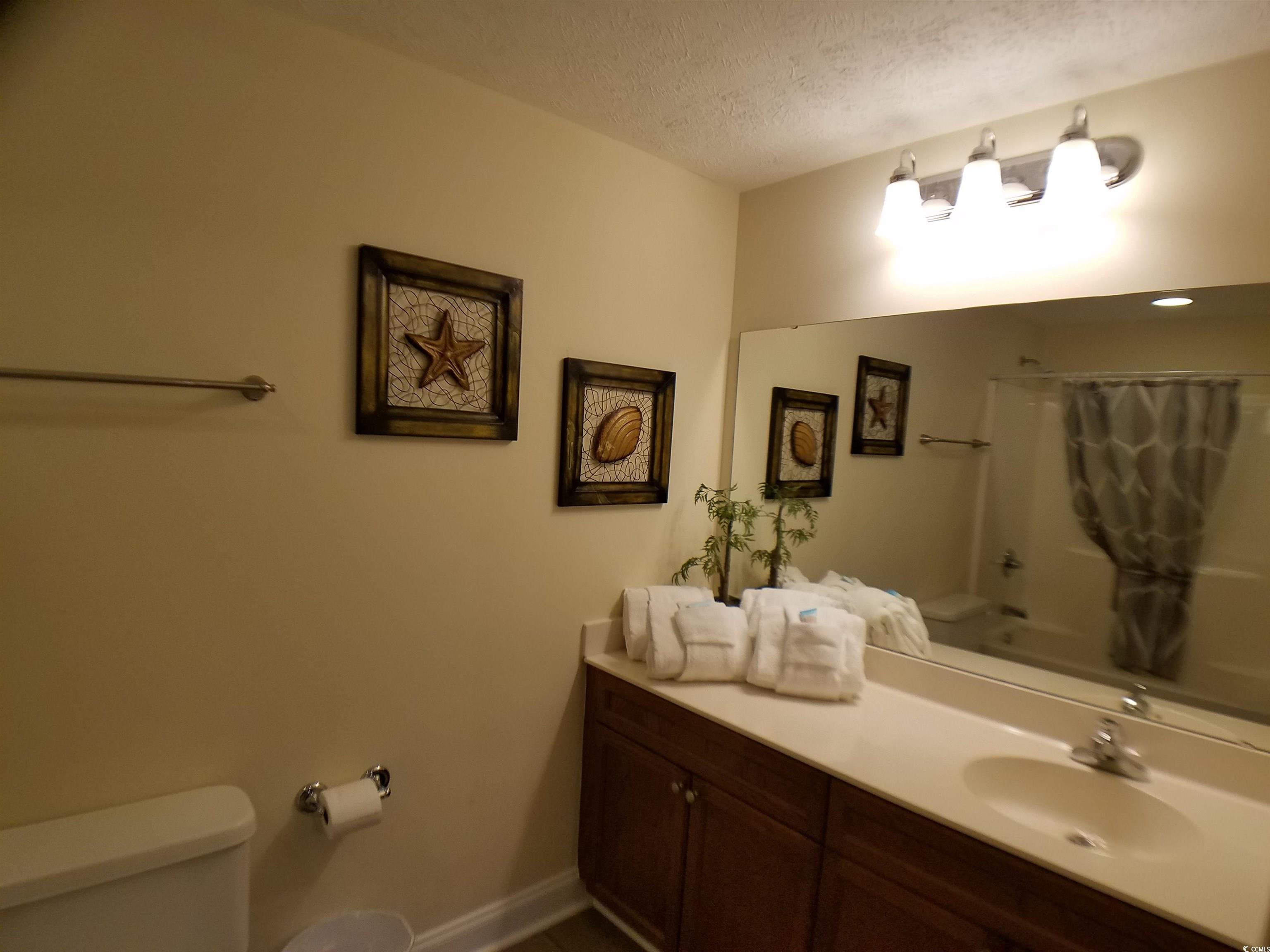 704 South Ocean Boulevard, Unit 101B Myrtle Beach, SC 29577 - Photo 16 of 25 Full bath featuring vanity, a textured ceiling, and shower / bath combo with shower curtain
