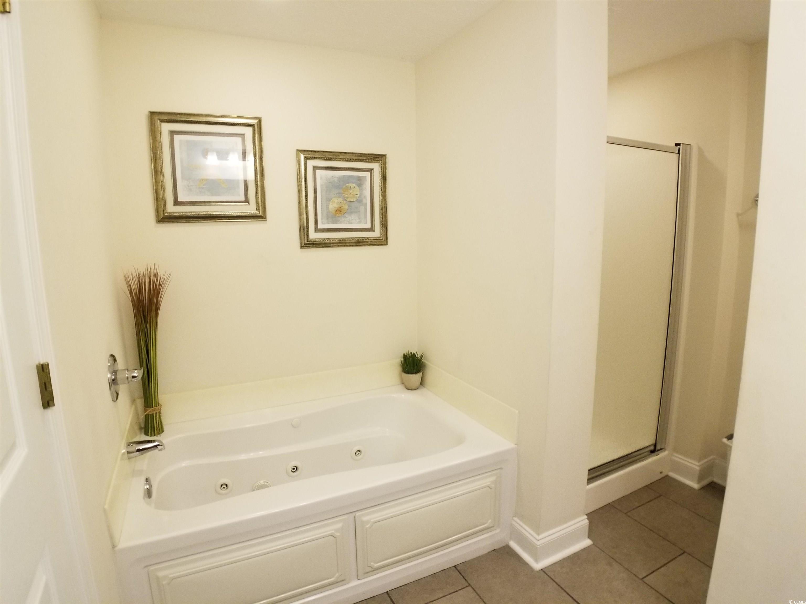704 South Ocean Boulevard, Unit 101B Myrtle Beach, SC 29577 - Photo 10 of 25 Full bath featuring tile patterned floors, a whirlpool tub, and a stall shower
