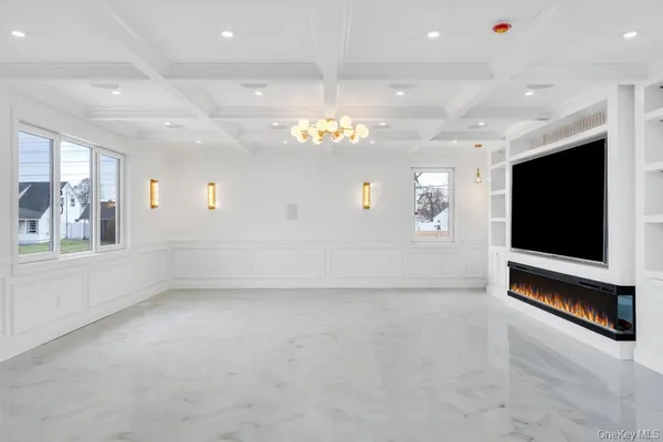 a view of an empty room with a window and a kitchen