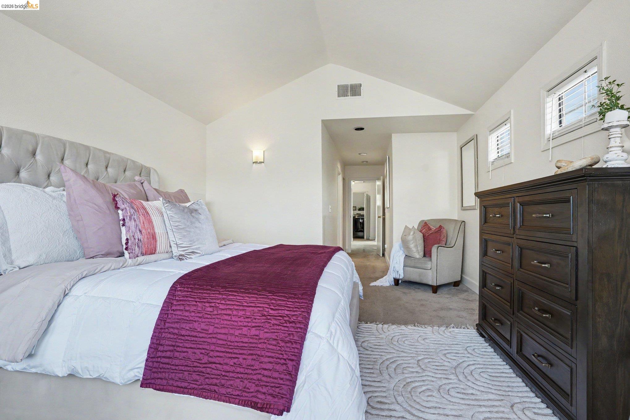1433 Myrtle Street Oakland, CA 94607 - Photo 12 of 25 Vaulted ceilings enhance this carpeted bedroom featuring multiple windows, a wall sconce, and a hallway entry